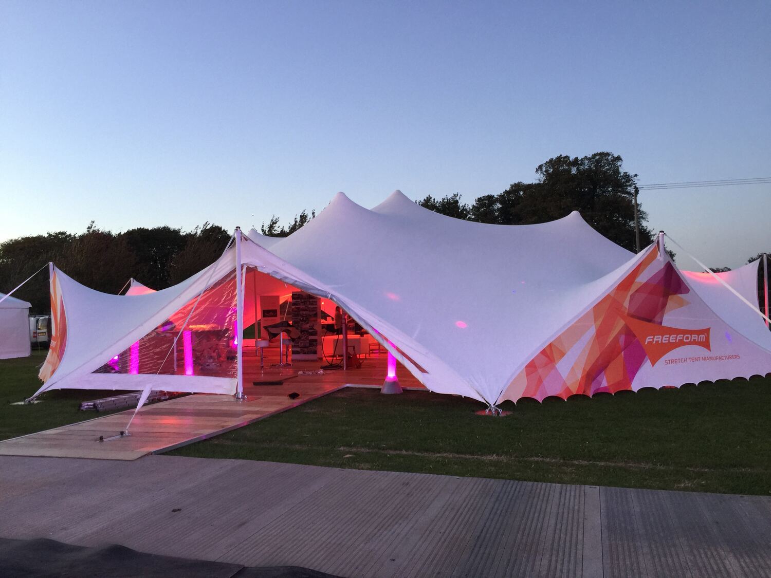 A white stretch tent lit pink at dusk